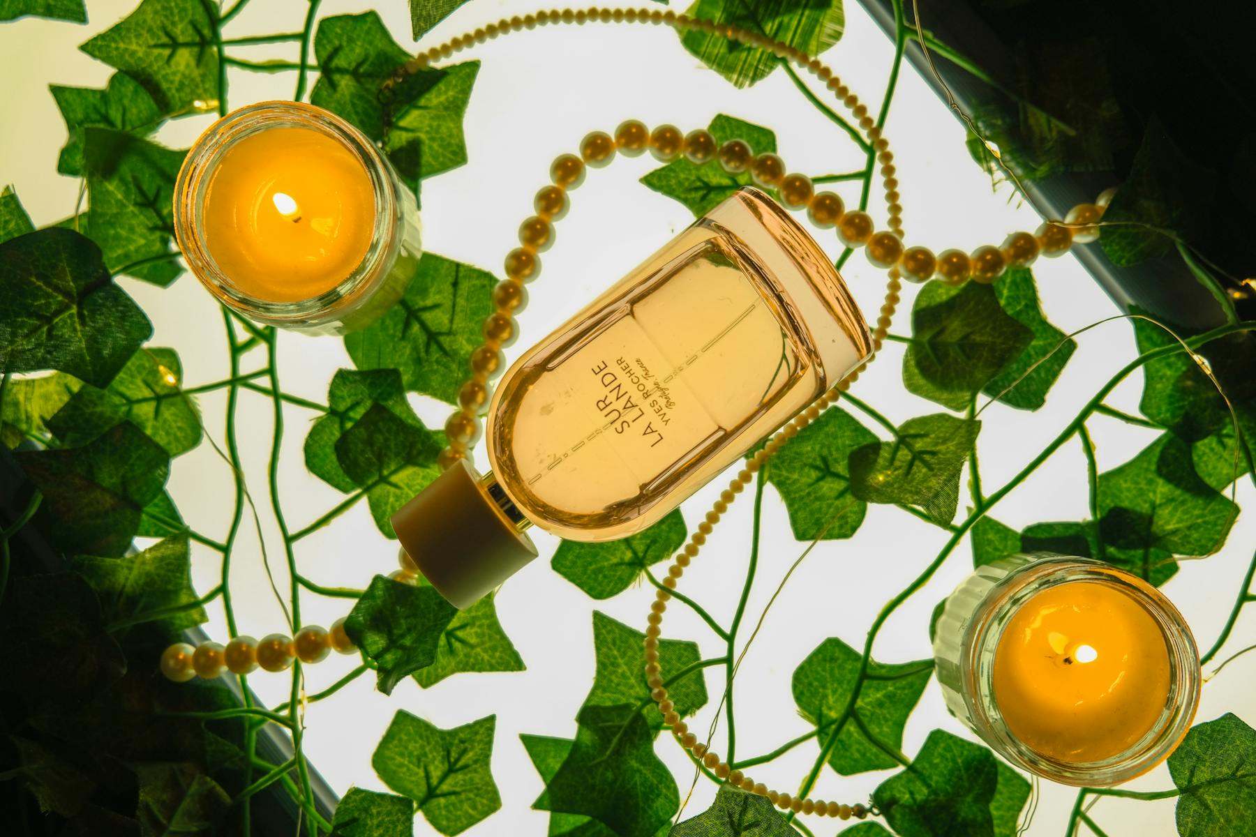 Perfume y velas decorativas sobre una superficie clara