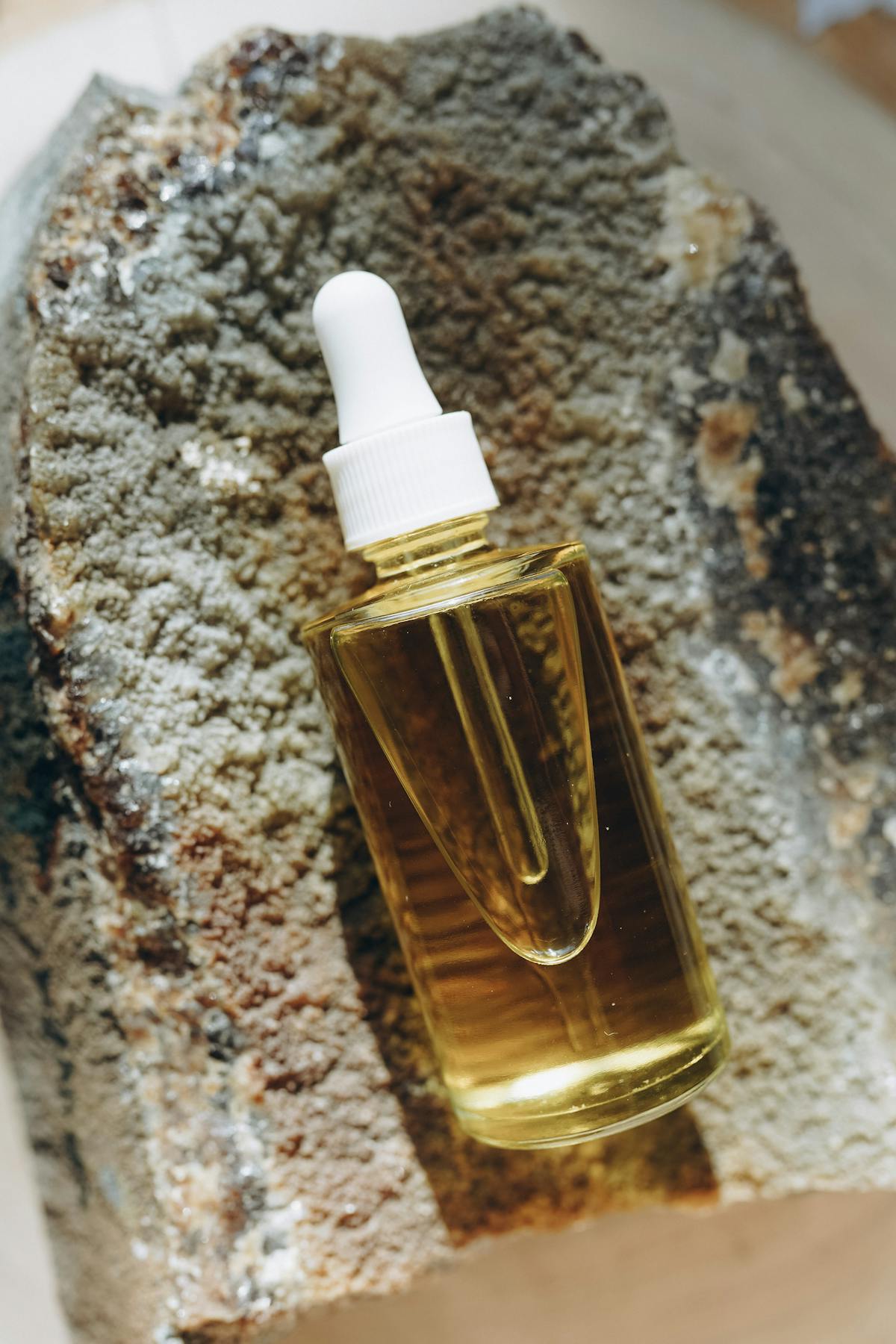 Gotero con aceite dorado sobre una piedra natural